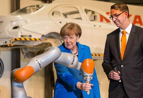 资料图片：2015年3月13日，德国奥格斯堡，德国总理默克尔造访库卡工业机器人生产工厂，亲自测试机器人手臂。（视觉中国）